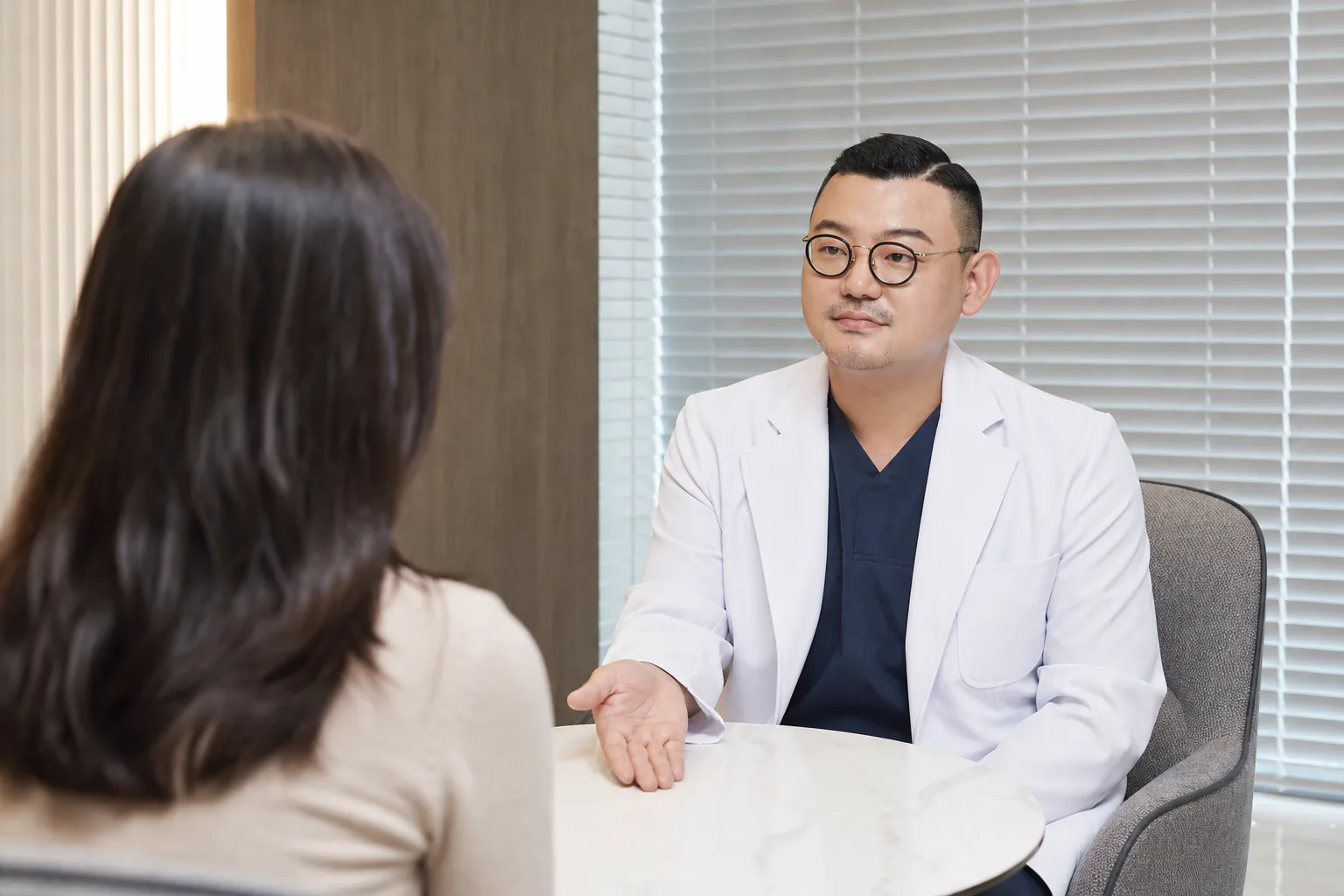 Dr. Hongseok Kim explaining the jaw and facial muscles to a patient in the consultation room at VOS Dermatology, Gangnam