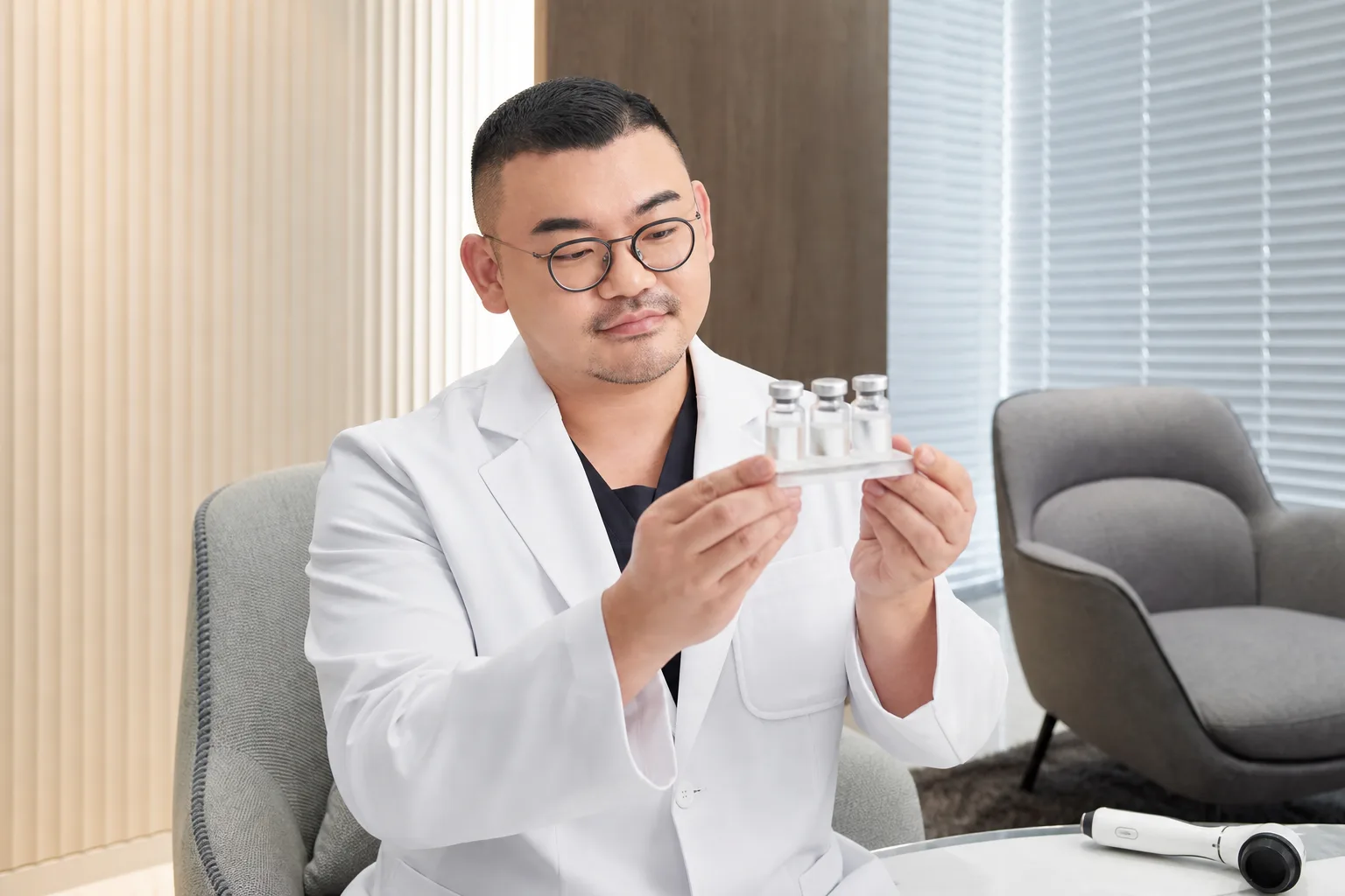 Dr. Hongseok Kim, board-certified dermatologist, examining skin-booster vials in the VOS consultation room, Gangnam